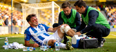 足球运动员受伤倒地接受治疗